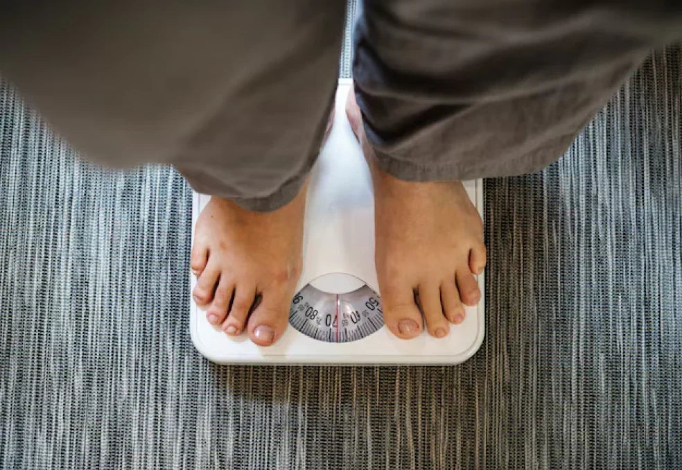 Person standing on a bathroom scale, illustrating that weight alone doesn't show quality of weight loss